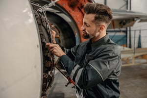 male-aviation-mechanic-repairing-aircraft-in-hanga-2022-02-14-13-51-34-utc
